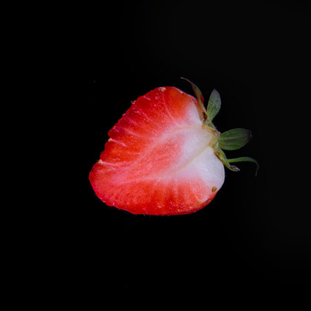 Strawberries cut in half on black background close up, copy space