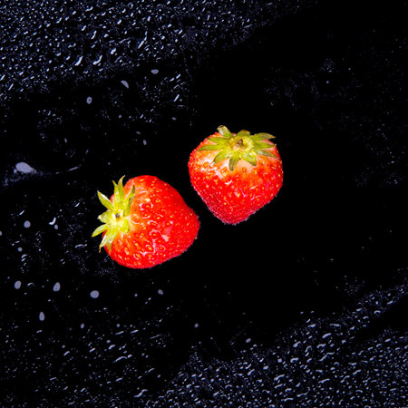 Strawberries with water drops on a black background close up, copy spaceの写真素材