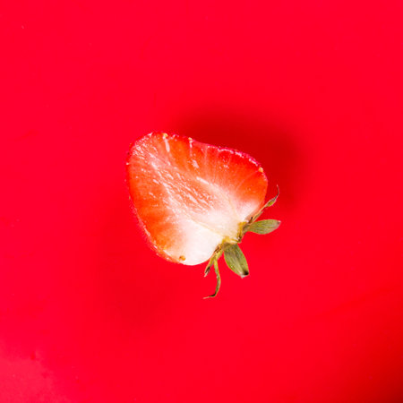 Half strawberry on red background isolated top view, copy spaceの写真素材