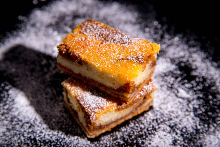 Besquit, cake on a black background, sprinkled with powdered sugar, dark and light layer of beckett...