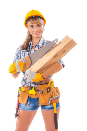 Halfl length portrait of happy female construction worker with handsaw and wooden planksl and tool belt standing isolated over white backgroundの写真素材