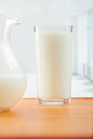 glass of milk and pitcher on tableの写真素材