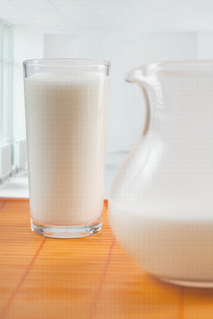 The jug and glass with milk stand on a tableの写真素材