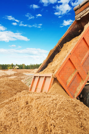 road works tipper unloadding sand at construction siteの写真素材