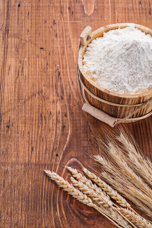 flour in wooden bucket with ears of wheat on old tableの写真素材