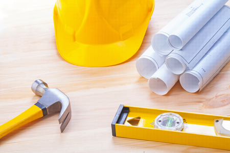 white blueprints construction level yellow helmet claw hammer on