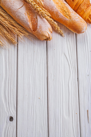 baguettes and croissant wheat ears on wooden boards with copyspaの写真素材