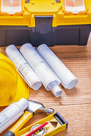 rolled blueprints helmet hammer level toolbox on wooden boardの写真素材