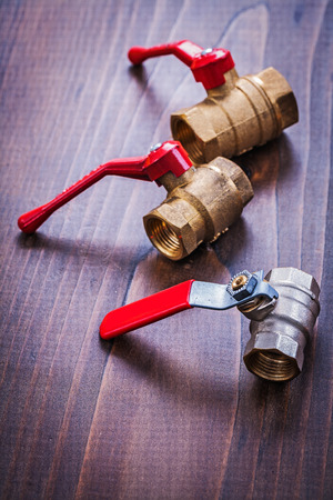 three plumbers fixtures with red handles on vintage wooden boardの写真素材