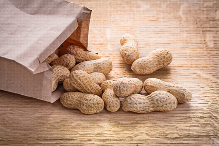 horizontal vercion peanuts poured from paper bag on wooden boardの写真素材