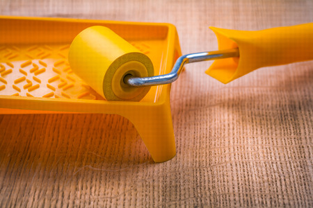roller on paint tray and wooden board