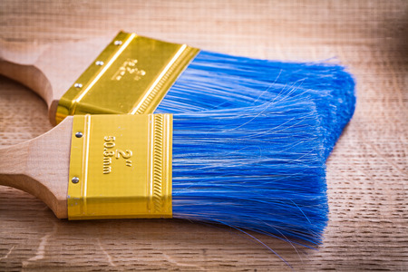 two paint brushes on wooden board very close up