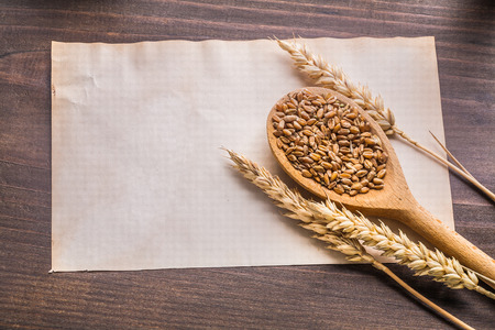 wooden spoon with coens of wheat and ears on old paper vintageの写真素材