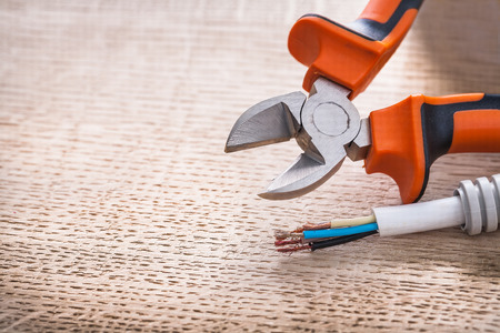 opened nippers and electrical cable on wooden board construction
