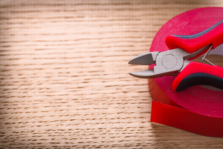 red nippers and insulating tape on wooden boardの写真素材