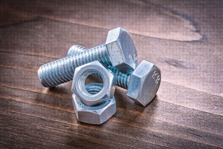 Couple of steel bolt details and screw nuts on vintage brown wooden board