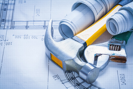Adjustable spanner rolled up blueprints and claw hammer construcの写真素材