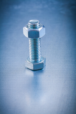 Stainless screw bolt with construction nut on metallic backgrounの写真素材