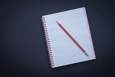 White checked copybook with red pencil on black background educa