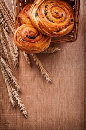 Wicker basket with raisin pastry wheat ears on oaken wooden boarの写真素材
