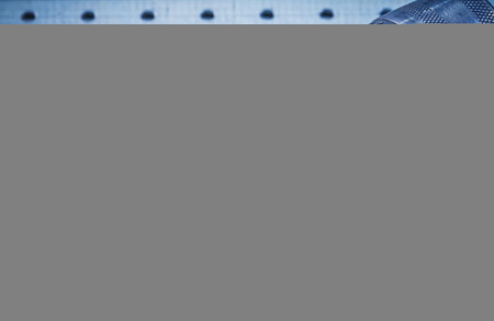 Metal drill on perforated metallic background construction conce