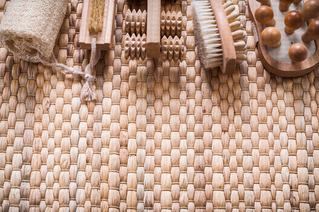 Scrubbing brush wooden massagers and loofah on wicker background healthcare conceptの写真素材