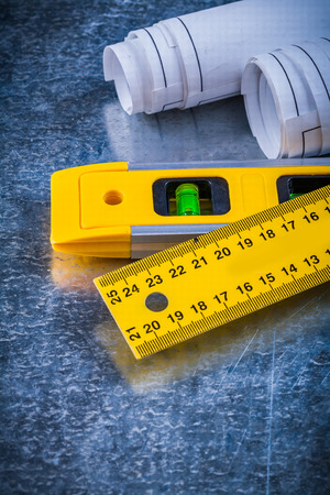 Close image of rolled up blueprints ruler and construction level on metallic scratched background maintenance concept.の写真素材