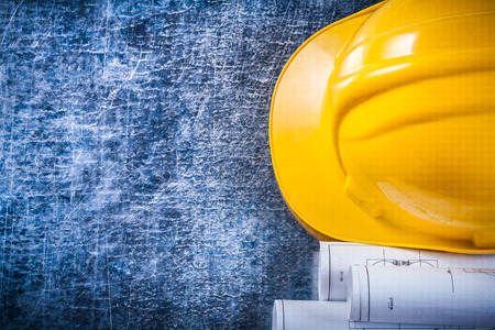 Copy space image of blueprint rolls and construction helmet on metallic scratched background building and architecture concept.の写真素材