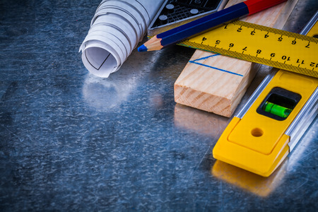 Pencil try square blueprints wooden brick and construction level on metallic scratched surface...
