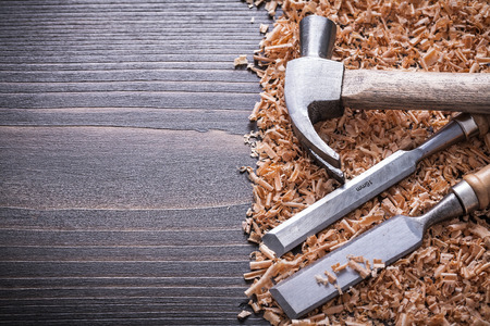 Claw hammer flat chisels and wooden shavings on vintage wood board copy space image construction...
