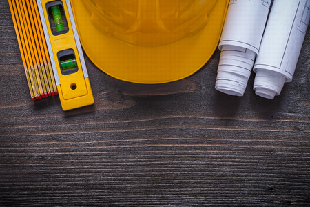 Blueprints yellow construction level building helmet and wooden meter on vintage wood board maintenance concept.の写真素材