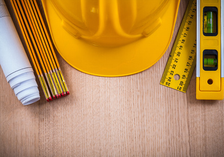 Protective helmet instruments of measurement blueprints and construction level on wooden board architecture and building concept.の写真素材