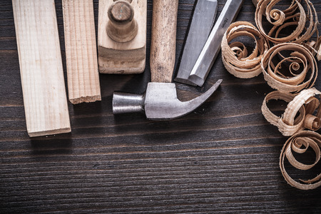 Vertical view of planer hammer chisels wooden studs and curled shavings on vintage wood board...