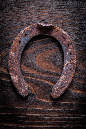 Rusty longstanding horsehoe on vintage dark wooden board construction concept.の写真素材