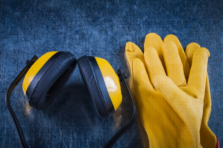 Protective yellow earmuffs and leather gloves on scratched metallic surface construction concept.の写真素材