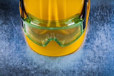 Close up view of building helmet and transparent protective glasses on scratched metallic background construction concept.の写真素材