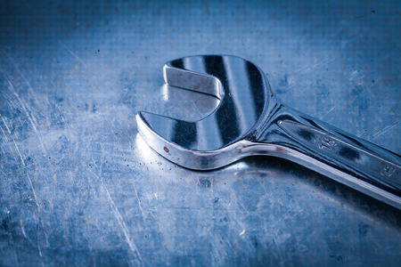Stainless hook wrench on scratched metallic background close up view construction concept.の写真素材