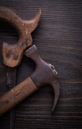 Set of rusted handsaw and claw hammer on wooden board.の写真素材