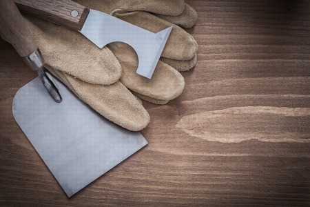 Surfacer bricklaying trowel and leather construction gloves on wood board.の写真素材
