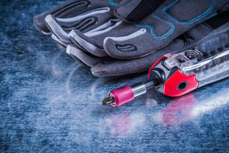 Threaded multi function screwdriver fabric protective gloves on metallic background.