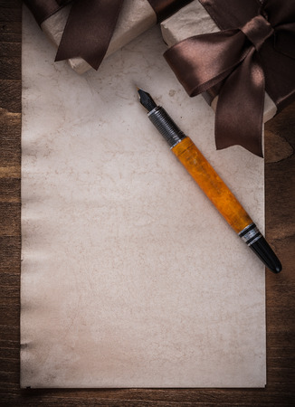 Present boxes tied bow paper fountain pen on wood board.の写真素材