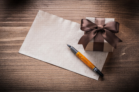 Gift box bow paper fountain pen on vintage wooden board.の写真素材