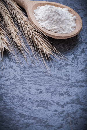Wooden spoon with flour golden wheat ears on black background.の写真素材
