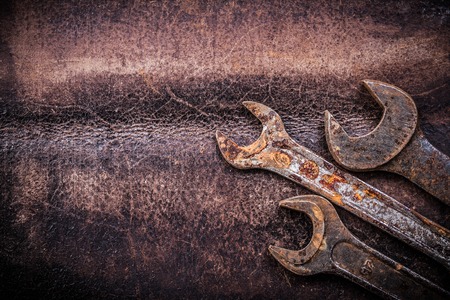 Rusty spanner wrenches on vintage leather construction concept.