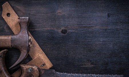 Collection of vintage rough construction tools on wooden board.