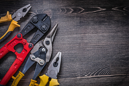 Composition of tin snips steel cutter pliers on wooden background.