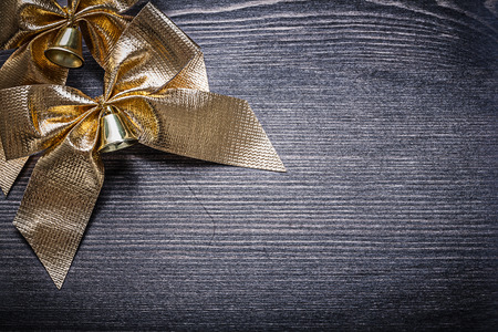 Christmas gold-shining knots with bells on wooden board holiday concept.の写真素材