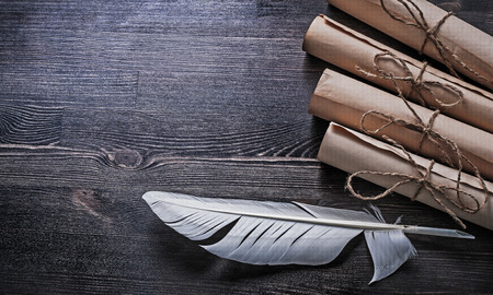 Feather vintage paper rolls with string on wooden board.の写真素材