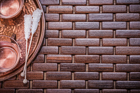 Copper tray tea cups and sugar sticks on wooden mat.の写真素材