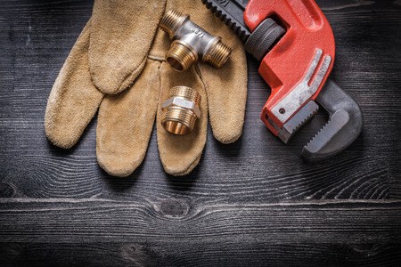Adjustable wrench pipe fittings safety gloves on wooden board.の写真素材